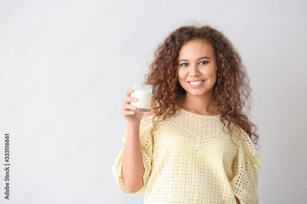 African-American woman with milk on light background