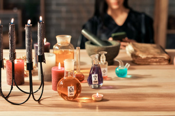 Bottles with potions and candles on table of alchemist