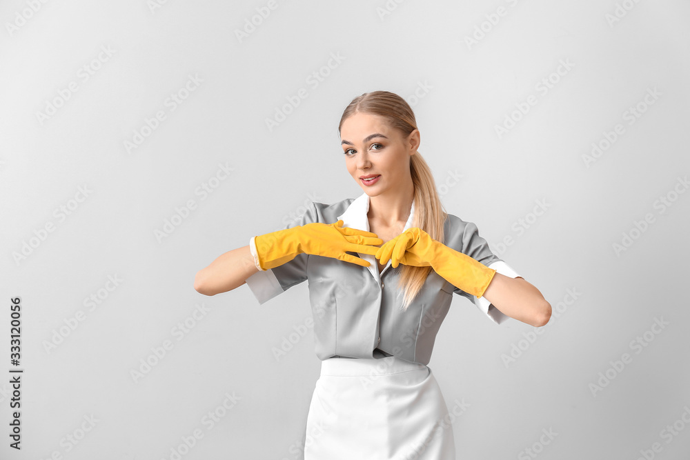 Beautiful young chambermaid on light background