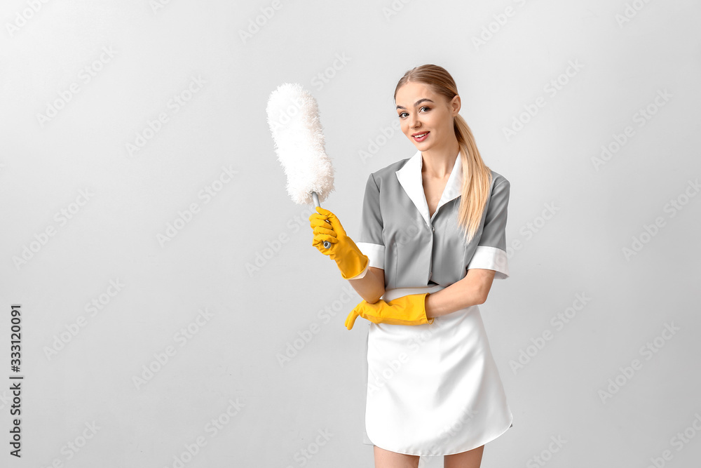 Beautiful young chambermaid on light background
