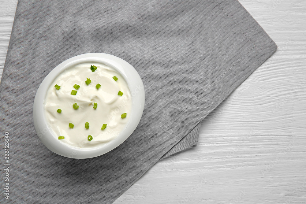 Bowl of tasty sour cream on table