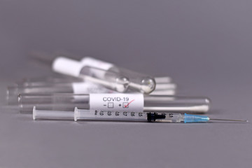 Wall Mural - syringe with medical test tube sample for coronavirus with label covid-19 in blurry background, conc