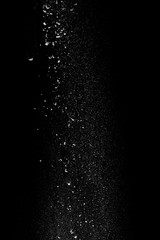  White powder in the form of snow or flour falls from top to bottom isolated on black background