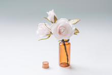 Artfully Made Artificial White Rose In A Dark Glass Vase On A White Background