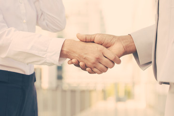 Wall Mural - Business professionals shaking hands. Business man and woman in office clothes meeting outside. Greeting gesture concept