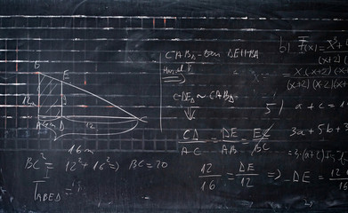 Maths formulas written by white chalk on the blackboard background.