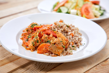 Wall Mural - meat with buckwheat and salad on the wooden background