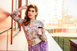 © Вячеслав Чичаев - Photo in bright weather of a fashionable glamorous beautiful woman with long hair against the background of the spring city in the sun. Model is standing outdoors with a cup of coffee in her hands.