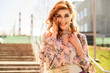 © Вячеслав Чичаев - Portrait of a happy stylish beautiful woman with long hair on the background of the steps of the building in spring in the sun in bright weather.