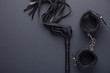 © Anton - Accessories for bdsm on a black background. Leather lash and leather handcuffs. Valentine's Day. Erotic shop. Copy space
