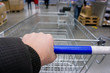 © Алексей Филатов - Male hand holds handle of a shopping cart rolls on tile in the store. First-person view close up.