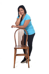 Wall Mural - woman playing with a chair in white background, leaning on the chair