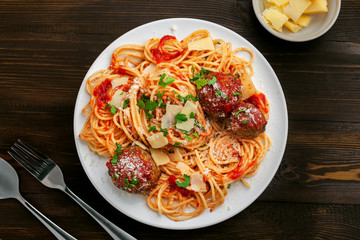 Wall Mural - Italian meal made of pasta on a wooden table. Plate of traditional American spaghetti with meatballs and tomato sauce. Top view shot directly above.