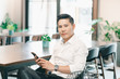 © Me studio - business asian man lifestyle in workplace office. smart male asian holding smart phone social distance online.