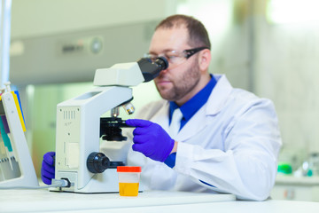  Laboratory worker performing urinalysis using microscope and laboratory equipment in a medical laboratory