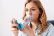 © LIGHTFIELD STUDIOS - selective focus of asthmatic woman using inhaler with spacer