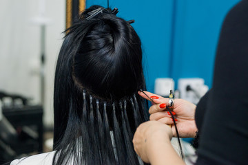 Professional woman applying hair extensions with different types of grips. Nano rings extensions made from real humas hair.