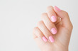 Beautiful groomed woman hand with pastel pink nails on light gray background. Manicure, pedicure beauty salon concept. Empty place for text or logo. Closeup.