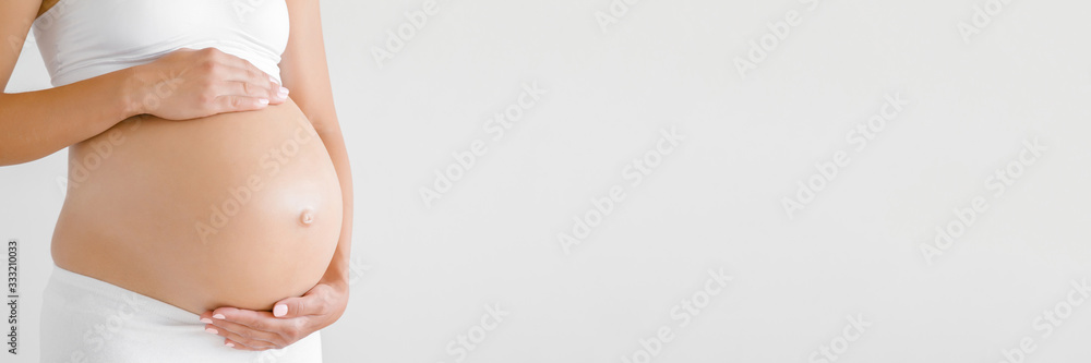 Woman hands touching naked belly. Isolated on light gray background. Emotional loving pregnancy time - 37 weeks. Baby expectation. Side view. Banner. Empty place for text, quote, saying. Closeup. - obrazy, fototapety, plakaty 