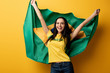 © LIGHTFIELD STUDIOS - excited female football fan holding brazilian flag on yellow