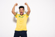 © LIGHTFIELD STUDIOS - excited african american football fan in yellow t-shirt with brazil sign gesturing and yelling on grey