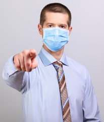 A man in a light shirt, tie and medical mask pokes his finger into a cell isolated