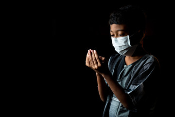 Muslim Boy Wearing a surgical mask Praying. Covid-19 Coronavirus concept. Shallow depth of field & copy space.