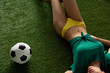 © LIGHTFIELD STUDIOS - cropped view of sexy girl lying with football ball on green grass