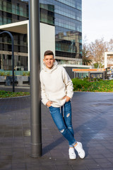 Wall Mural - Portrait of young male with hands on pocket leaning on pole outside