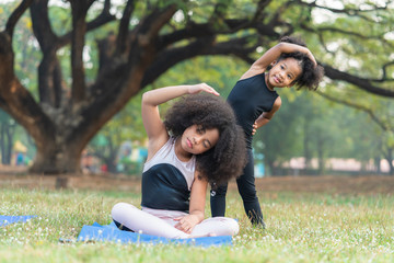 Wall Mural - African american older sister and younger sister practicing yoga in the park outdoor