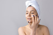 © Mountains Hunter - Beauty portrait of woman in white towel on head applies cream to the face. Skincare cleansing eco organic cosmetic spa relax concept.