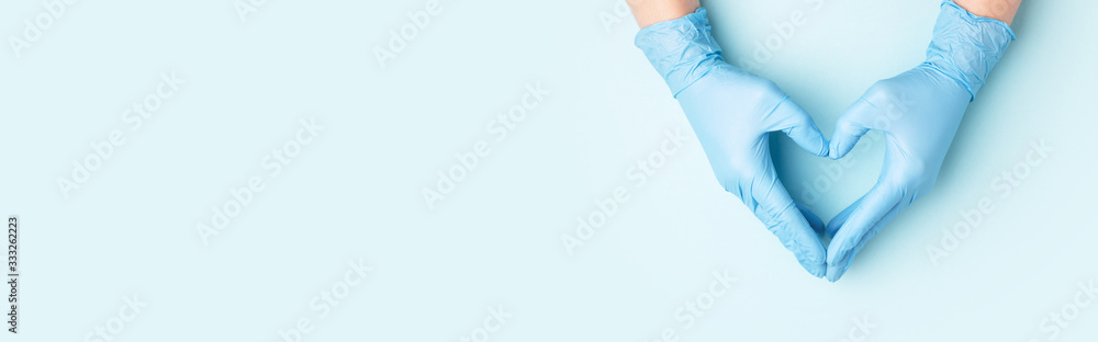 Hand in medical gloves in shape of heart on blue background. - obrazy, fototapety, plakaty 