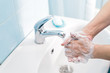 Woman washing hands with soap under the water tap