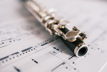  Close up and selective focus on a classic wooden flute on a background of unidentifiable sheet music