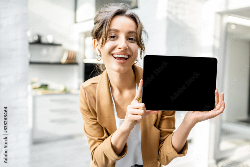 Well-dressed cheerful business woman with a digital tablet indoors, showing tablet with a black screen to copy paste - obrazy, fototapety, plakaty 