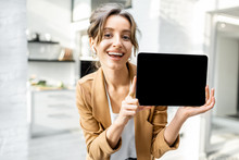 Well-dressed Cheerful Business Woman With A Digital Tablet Indoors, Showing Tablet With A Black Screen To Copy Paste