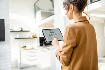 woman controlling smart home devices using a digital tablet with launched application in the white l