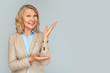 © JENOCHE - Portrait of business woman pointing up and looking at the camera over gray background .