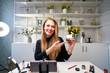 © artiemedvedev - Beauty blogger woman filming daily make-up routine tutorial near camera. Influencer girl live streaming cosmetics product review. Vlogger female recommends eye shadow palette showing thump up sign.