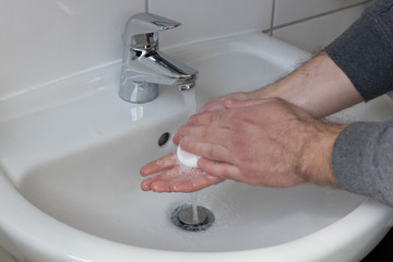 Detail of a Young male washing his Hands with Soap under running water in order to reduce infection Risk during corona Virus pandemic