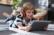 © New Africa - Cute little boy with headphones and tablet listening to audiobook at home