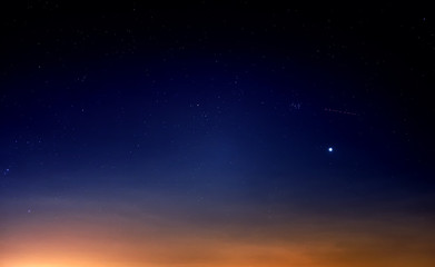 blue starry sky landscape at dusk against red sunset clouds background wide view of universe with st