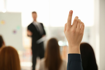 Wall Mural - Young woman raising hand to ask question at business training indoors, closeup