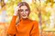 © Надежда Манахова - Beautiful young woman on a street in a park in October. The girl is dressed in sweater and in glass, round glasses. Student teacher is relaxing, walking in the park.