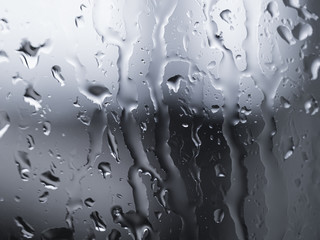 Rain water drops on glass over blur silver background,abstract texture pattern