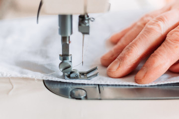 Womans hand sewing on the sewing mashine homemade medical mask.