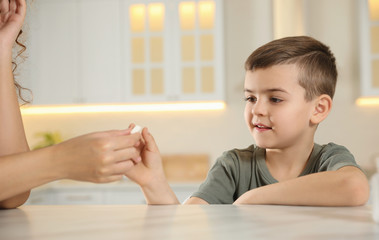 Wall Mural - African-American woman giving vitamin pill to little boy in kitchen