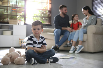 Sticker - Unhappy little boy feeling jealous while parents spending time with his sister at home