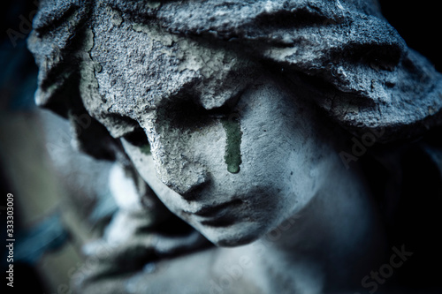 Fotomural Ancient stone statue of crying sad angel with tears in face as symbol of death and end of human life