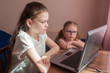 © Kiryakova Anna - Two girls, the oldest and the youngest, are engaged at a table on a laptop. Little sister with glasses.